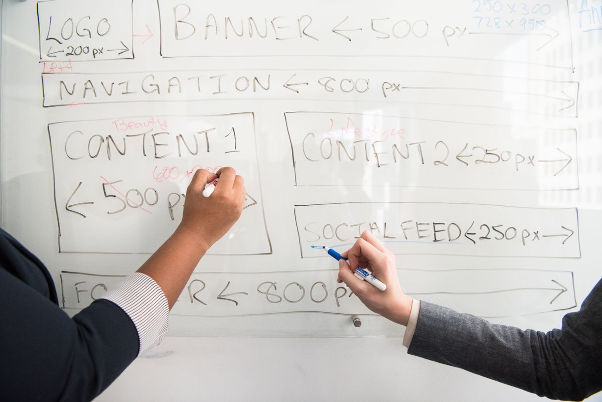 Two people sketching content placements on a whiteboard.